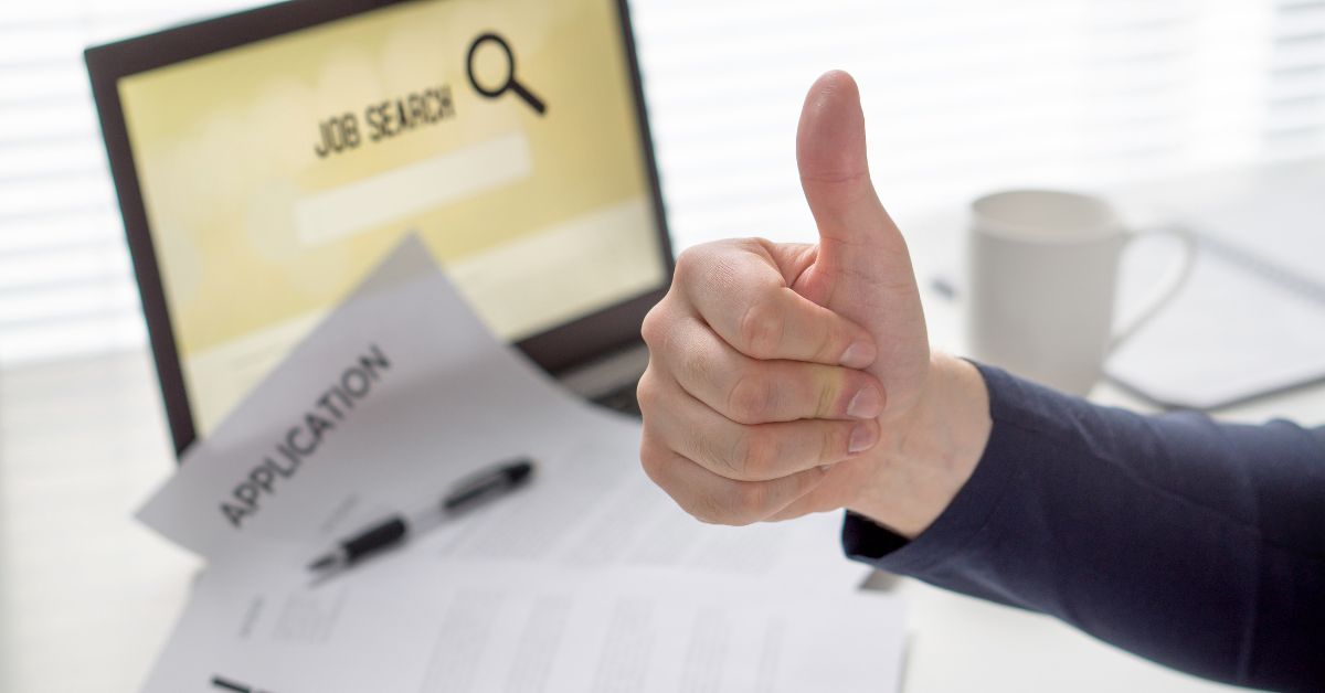 an image of a thumbs up with a laptop in the background that says job search on white background.