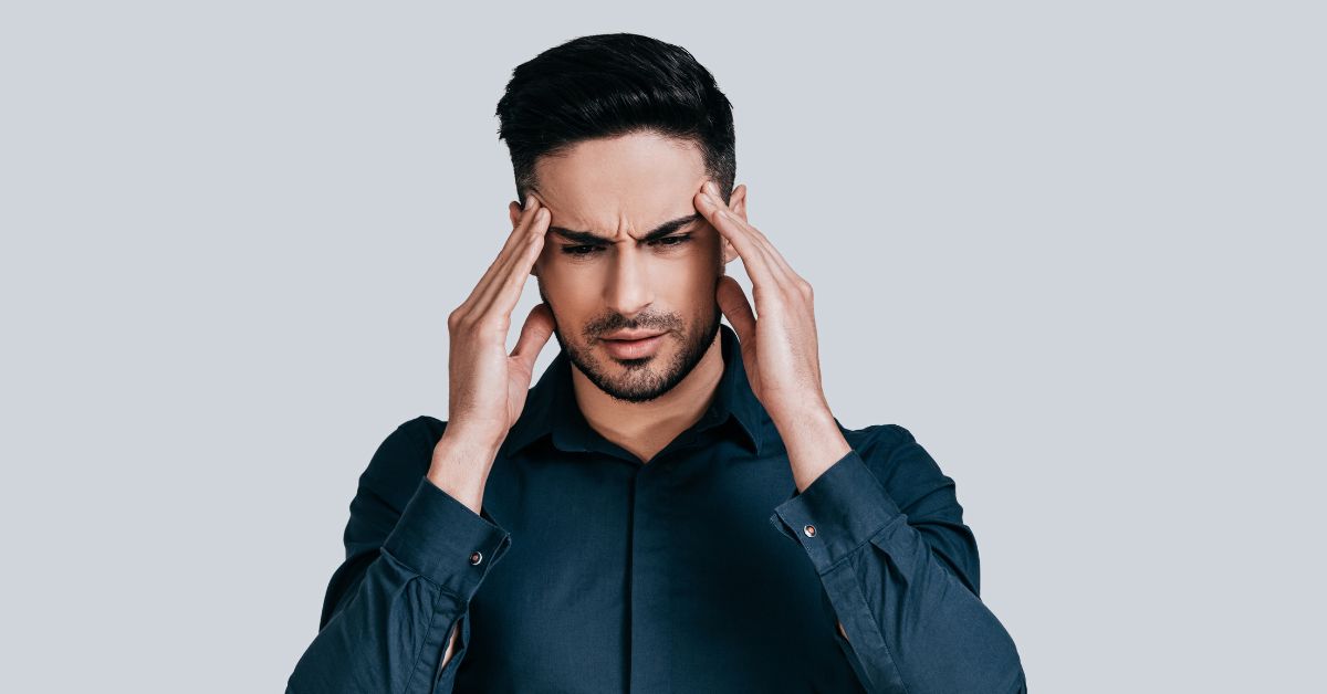an image of a male holding his head with his two hands on a grey background