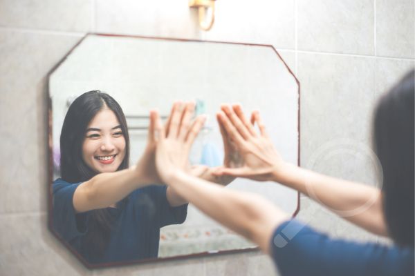 a woman looking at her reflection in the mirror discovering the importance of not self-sabotaging in sobriety